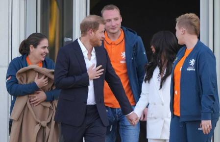 A la izquierda, una mujer arropa a su hijo con el abrigo de Markle