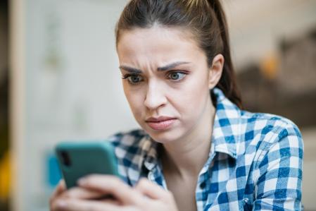 Mujer contrariada mientras consulta el WhatsApp