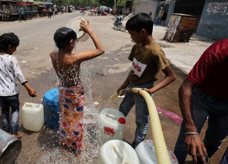 A boy bathes as he waits to collect water from a municipal tanker on a hot summer day in New Delhi, India, May 1, 2022. REUTERS/Anushree Fadnavis