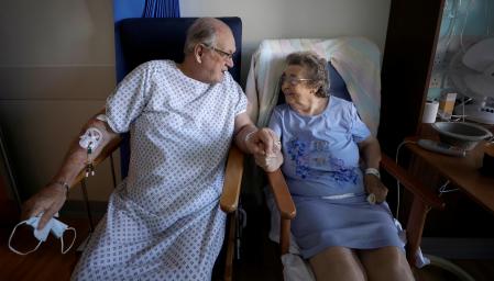 Coronavirus patients George Gilbert, 85 and his wife Domneva Gilbert 84, hold hands during a short visit as they are being treated in different areas, both part of the TACTIC-R trial, at Addenbrooke's hospital in Cambridge, Britain May 21, 2020. Picture taken May 21, 2020. The new trial known as TACTIC-R is testing whether existing drugs will help prevent the body's immune system from overreacting, which scientists hope could prevent organ failure and death in COVID-19 patients.  Kirsty Wigglesworth/Pool via REUTERS     TPX IMAGES OF THE DAY