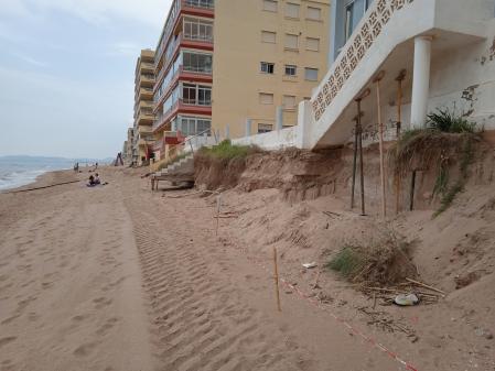 Edificio apuntalado y escaleras que ya no llegan a la arena y quedan suspendidas en el aire, en la playa de Tavernes de la Valldigna