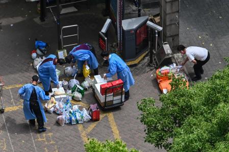 Workers receive deliveries at the entrance of a building during a Covid-19 coronavirus lockdown in the Jing'an district in Shanghai on May 8, 2022. (Photo by Hector RETAMAL / AFP)