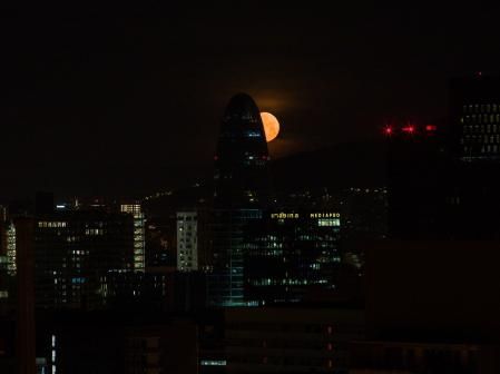La luna brillando entre los edificios.