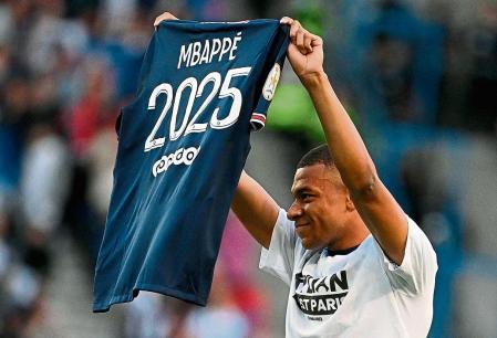 Paris Saint-Germain's French forward Kylian Mbappe poses with a jersey after the announcement he staying at PSG until 2025 before the French L1 football match between Paris Saint-Germain (PSG) and Metz at the Parc des Princes stadium in Paris on May 21, 2022. (Photo by Anne-Christine POUJOULAT / AFP)
