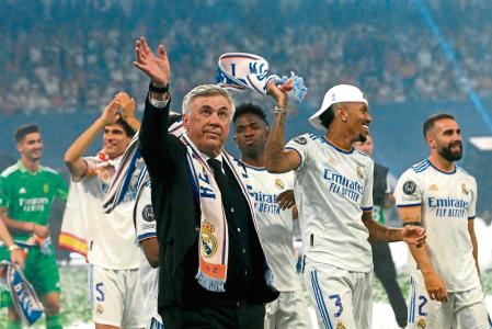 Real Madrid's Italian coach Carlo Ancelotti waves as he walks on the pitch with his players during the club's celebration of their 14th European Cup at the Santiago Bernabeu stadium in Madrid on May 29, 2022, a day after beating Liverpool in the UEFA Champions League final in Paris. - Real Madrid claimed a 14th European Cup as Vinicius Junior's goal saw them beat Liverpool 1-0 in the Champions League final at the Stade de France amid chaotic scenes yesterday. (Photo by OSCAR DEL POZO / AFP)