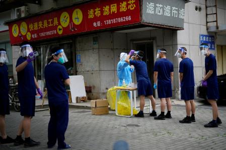 Los bomberos con máscaras y protectores faciales se alinean para las pruebas de ácido nucleico, después del bloqueo establecido para frenar la enfermedad del coronavirus
