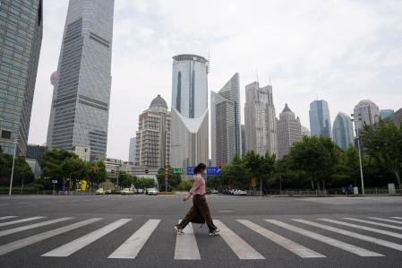 Un peatón con mascarilla cruza una calle frente a torres de oficinas en el distrito financiero de Lujiazui