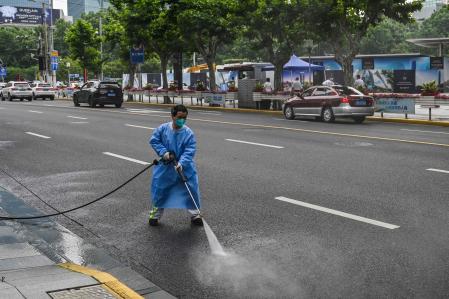 Un trabajador con equipo de protección limpia una calle en el distrito Jing'an de Shanghai