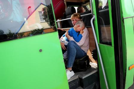 A woman carries a child as they travel on an evacuation convoy from Russian troops' occupied Kupiansk town, amid Russia's attack on Ukraine, on the outskirts of Kharkiv, Ukraine May 30, 2022. Picture taken May 30, 2022. REUTERS/Ivan Alvarado