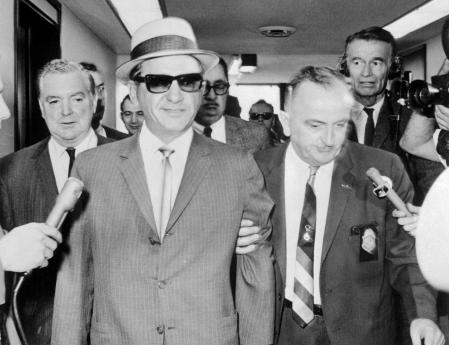 Sam Giancana (con gafas de sol) bajo custodia policial en 1965