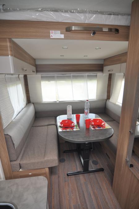 Zona comedor con cama abatible adosada al techo en el modelo Burstner Premio Plus 510TK