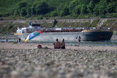 A ship sails through the narrow channel left by the low water in the Rhine while people watch from the sandbanks in Osterpai, Germany, August 16. 2022. REUTER/Benjamin Westhoff