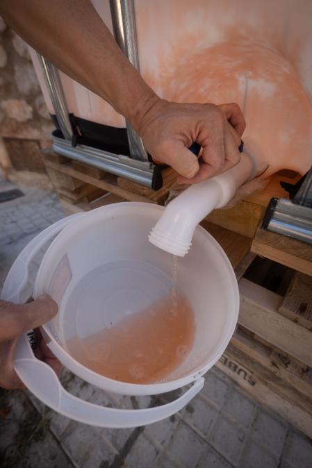 Un vecino de Vacarisses (Barcelona) abre el grifo de uno de los bidones para abastecimiento y el agua sale roja.