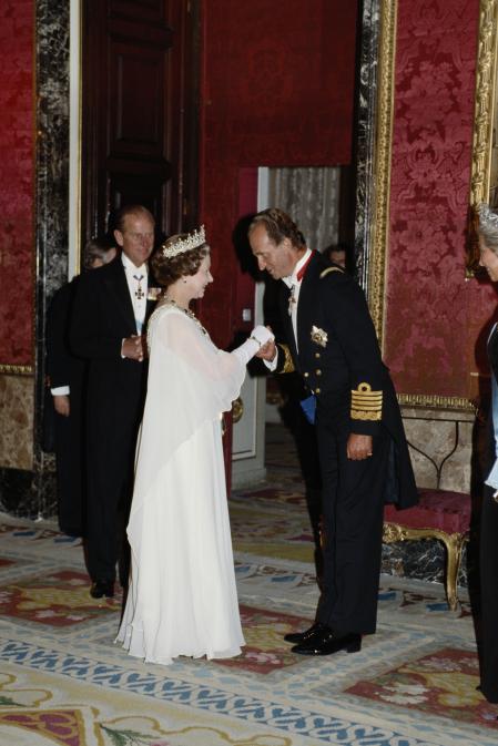 El rey Juan Carlos I besa la mano de la monarca británica en el salón del trono del palacio real de Madrid.