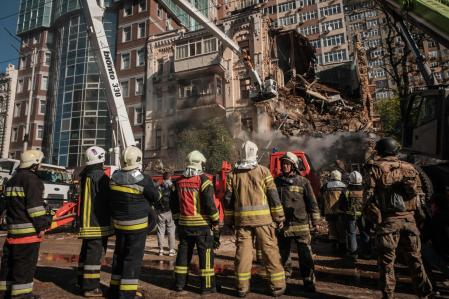 Ukrainian firefighters works on a destroyed building after a drone attack in Kyiv on October 17, 2022, amid the Russian invasion of Ukraine. - Ukraine officials said on October 17, 2022 that the capital Kyiv had been struck four times in an early morning Russian attack with Iranian drones that damaged a residential building and targeted the central train station. (Photo by Yasuyoshi CHIBA / AFP)