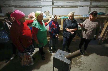 Local women gather in a bomb shelter around a wood stove delivered by volunteers, amid Russia's attack on Ukraine, in the village of Lupareve near a frontline in Mykolaiv region, Ukraine October 18, 2022. REUTERS/Valentyn Ogirenko