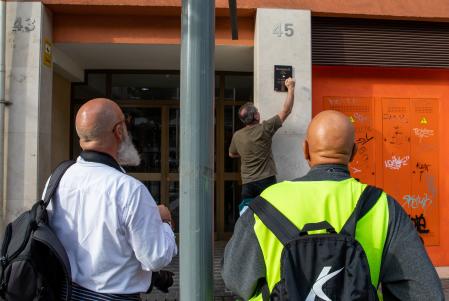 Dos personas contemplan la colocación de una placa