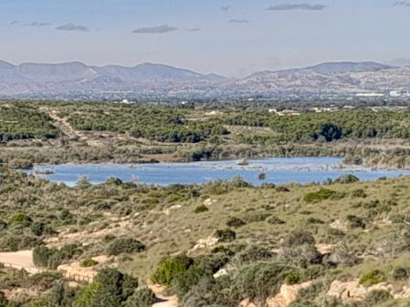 Vista de la gran charca, los bancales de cultivos abandonados y las sierras del interior.