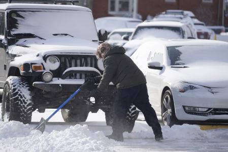 A man clears a path to vehicles parked in a lot Thursday, Dec. 22, 2022, in Denver. Temperatures plunged far and fast Thursday as a winter storm formed ahead of Christmas weekend, promising heavy snow, ice, flooding and powerful winds across a broad swath of the country and complicating holiday travel. (AP Photo/David Zalubowski)
