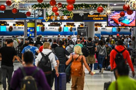 Travelers walk through Miami International Airport during a winter storm ahead of the Christmas holiday in Miami, Florida, on December 23, 2022. - Nearly a million-and-a-half US power customers were in the dark Friday as a severe winter storm walloped the country, causing highway closures and thousands of flight cancellations days before Christmas. Heavy snow, howling winds, and air so frigid it instantly turned boiling water into ice took hold of much of the nation, including normally temperate southern states. (Photo by CHANDAN KHANNA / AFP)