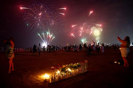 Los brasileños celebran con fuegos artificiales el inicio del Año Nuevo en la playa de Gonzaga, en Santos, Brasil, donde mañana tendrá lugar el funeral del ícono del fútbol brasileño, Edson Arantes do Nascimento, más conocido como Pelé