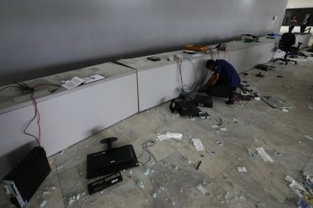 Un trabajador inspecciona los ordenadores destruidos en la entrada principal del Palacio de Planalto, en Brasilia, el día después de que los partidarios de Bolsonaro lo asaltaran