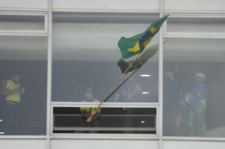 Un manifestante partidario del expresidente de Brasil Jair Bolsonaro ondea una bandera nacional brasileña desde una ventana después de asaltar el Palacio Planalto en Brasilia, el 8 de enero de 2023