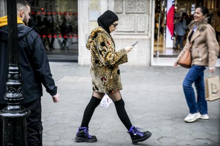 foto XAVIER CERVERA 11/01/2023 una mujer musulmana (con velo en la cabeza ,y gafas d sol) viste con abrigo d leopardo mickey mouse y con medias pantys por passeig d gracia, barcelona (en una mano el telefono mobil y en la otra una bolsa de compras)