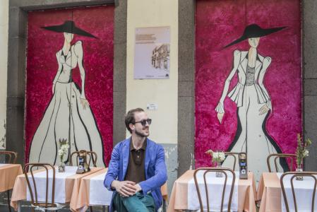 O Brinquinho restaurant.Tourist in a outdoor terrace. In background a painting,in Santa Maria street, this artwork is part of the project  (Projecto arte de portas abertas),This project aims to revitalize the old town , Funchal, Madeira