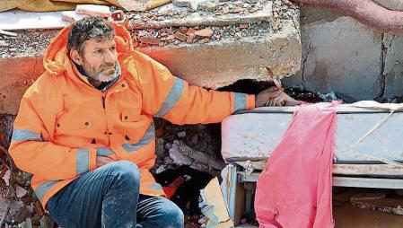 TOPSHOT - Mesut Hancer holds the hand of his 15-year-old daughter Irmak, who died in the earthquake in Kahramanmaras, close to the quake's epicentre, the day after a 7.8-magnitude earthquake struck the country's southeast, on February 7, 2023. - Rescuers in Turkey and Syria braved frigid weather, aftershocks and collapsing buildings, as they dug for survivors buried by an earthquake that killed more than 5,000 people. Some of the heaviest devastation occurred near the quake's epicentre between Kahramanmaras and Gaziantep, a city of two million where entire blocks now lie in ruins under gathering snow. (Photo by Adem ALTAN / AFP)