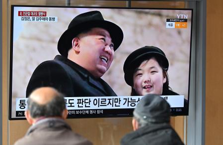 People watch a television screen showing a news broadcast with an image of North Korean leader Kim Jong Un (L) and his daughter presumed to be named Ju Ae (R) attending a military parade held in Pyongyang to mark the 75th founding anniversary of its armed forces, at a railway station in Seoul on February 9, 2023. - North Korea's Kim Jong Un oversaw a major military parade showcasing a record number of nuclear and intercontinental ballistic missiles, state media reported on February 9, including what analysts said was possibly a new solid-fueled ICBM. (Photo by Jung Yeon-je / AFP)