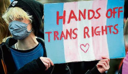 A Trans Rights activist holds a placard while taking part in the 