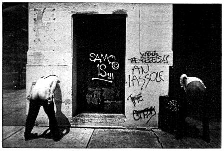 Los artistas, enseñando el trasero, junto a un pintada que dice que eran tontos del...