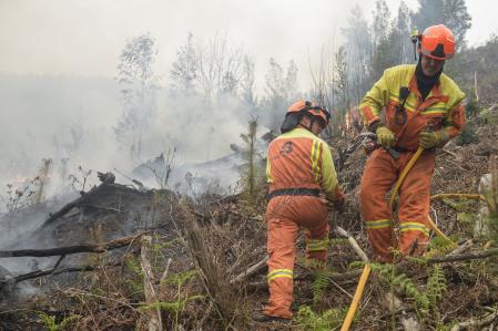 Los bomberos trabajan en un incendio declarado en Navelgas, Asturias