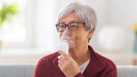 Mujer anciana que usa inhalador para el asma y enfermedades respiratorias