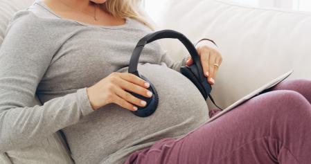 Shot of an unrecognizable pregnant woman playing music for her baby at home