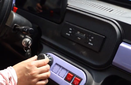 El conductor del pequeño eléctrico urbano sintoniza la radio del coche