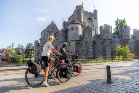 Ciclistas pedaleando delante del Castillo de Gravensteen en Gante.