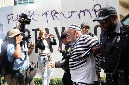 El manifestante Dominic Santana es detenido por agentes de la policía de Miami después de intentar apresurar la caravana del expresidente Donald Trump que salía del Palacio de Justicia Federal de los Estados Unidos Wilkie D. Ferguson Jr. después de que la lectura de cargos de Trump concluyera el 13 de junio de 2023 en Miami