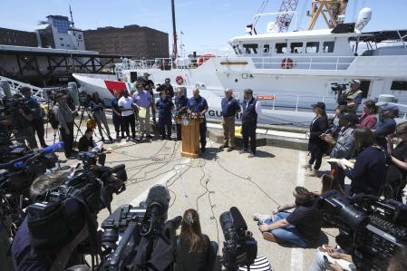 El capitán de la Guardia Costera de EE. UU., Jamie Frederick, en el centro del micrófono, se enfrenta a los reporteros durante una conferencia de prensa, el miércoles 21 de junio de 2023, en la Base de la Guardia Costera de Boston, en Boston.