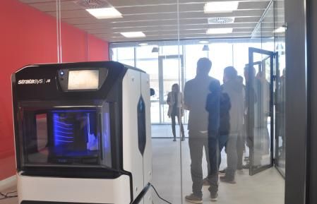 Grupo de empresarios escuchando la presentación sobre ThinkIn 3D Mataró y en primer plano una impresora 3D