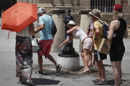Varias personas se refrescan en fuentes del centro de Sevilla
