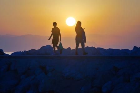 Dos personas caminando en el paseo de Fuengirola en el momento del amanecer.
