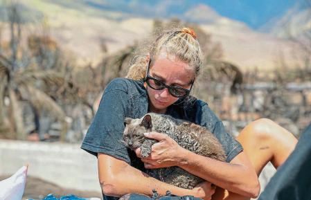 A woman cradles her cat after finding him in the aftermath of a wildfire in Lahaina, western Maui, Hawaii on August 11, 2023. A wildfire that left Lahaina in charred ruins has killed at least 67 people, authorities said on August 11, making it one of the deadliest disasters in the US state's history. Brushfires on Maui, fueled by high winds from Hurricane Dora passing to the south of Hawaii, broke out August 8 and rapidly engulfed Lahaina. (Photo by Moses SLOVATIZKI / AFP)