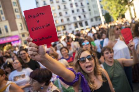 A demonstrator holds a red card reading in Spanish 