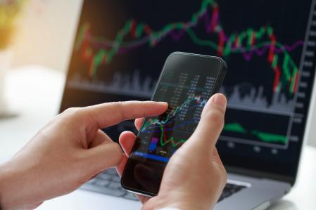 Inversor analizando el mercado financiero a través de la pantalla de un smartphone