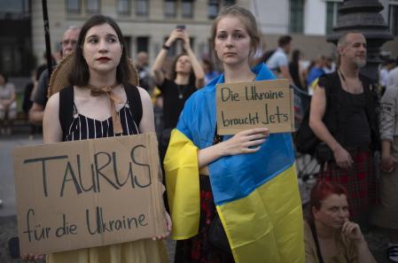 Two woman hold posters demanding Taurus cruise missiles and jets for Ukraine during at a rally to mark the 32nd anniversary of Ukraine's independence and to protest against the Russian war on Ukraine, in Berlin, Germany, Thursday, Aug. 24, 2023. (AP Photo/Markus Schreiber)
