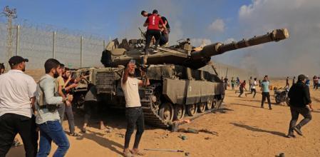 Un grupo de palestinos celebra la captura de un tanque israelí en la línea que separa Gaza de Israel, en la zona de Jan Yunis 
(AFP / Said Khatib)
