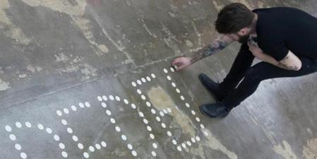 El artista Abel Azcona escribiendo la palabra Pederastia con hostias en 2015