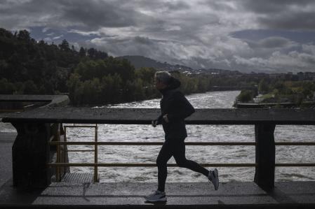 Un hombre corre ante el río Miño a su paso por el embalse de Velle en Ourense